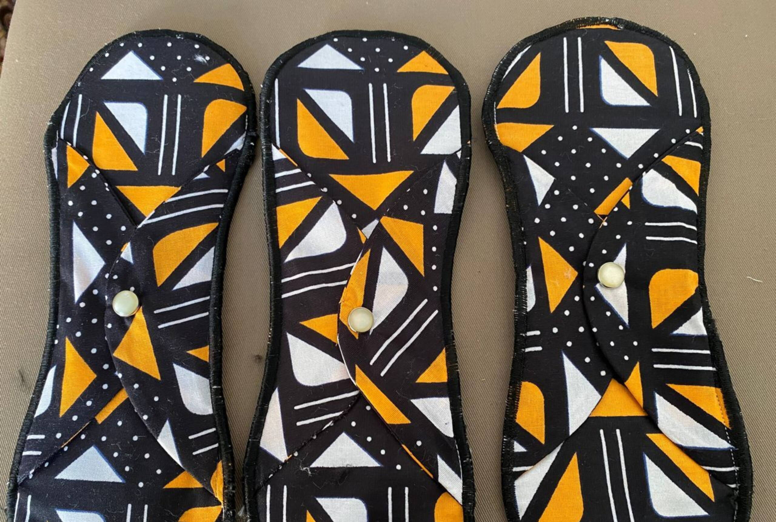 Wiederverwendbare Binden Drei Binden in farbigem Stoff.