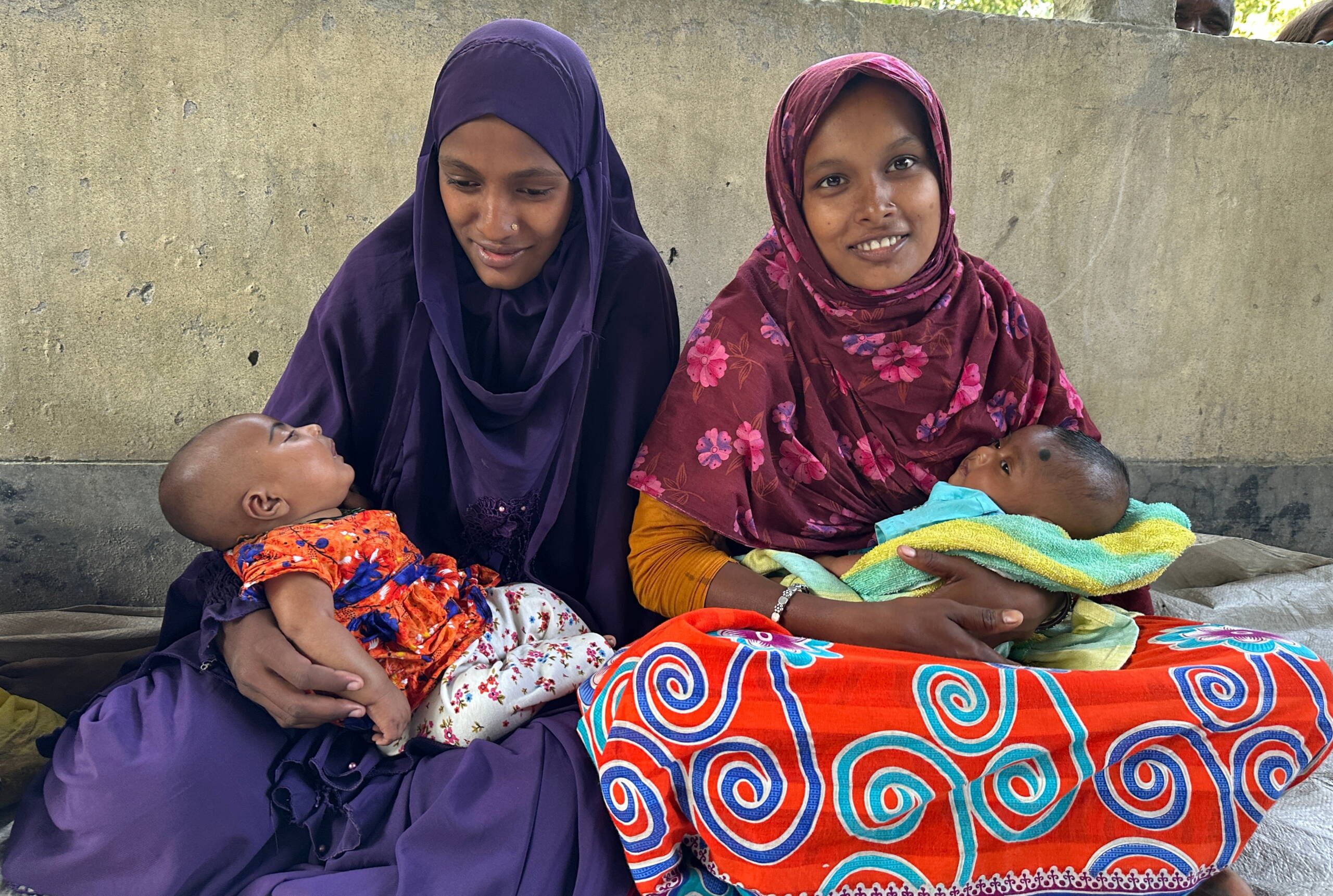 Zwei junge Mütter mit Baby auf Arm.