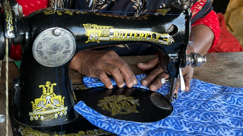 Nahaufnahme von Händen, die ein Lätzli nähen.