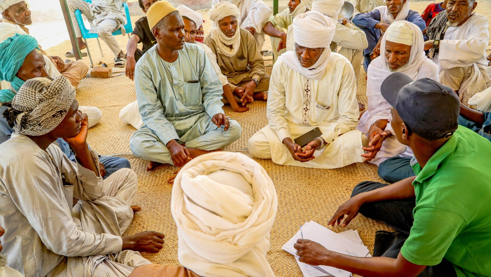 Männer sitzen im Kreis bei einer Gemeinschaftsbefragung im Tschad