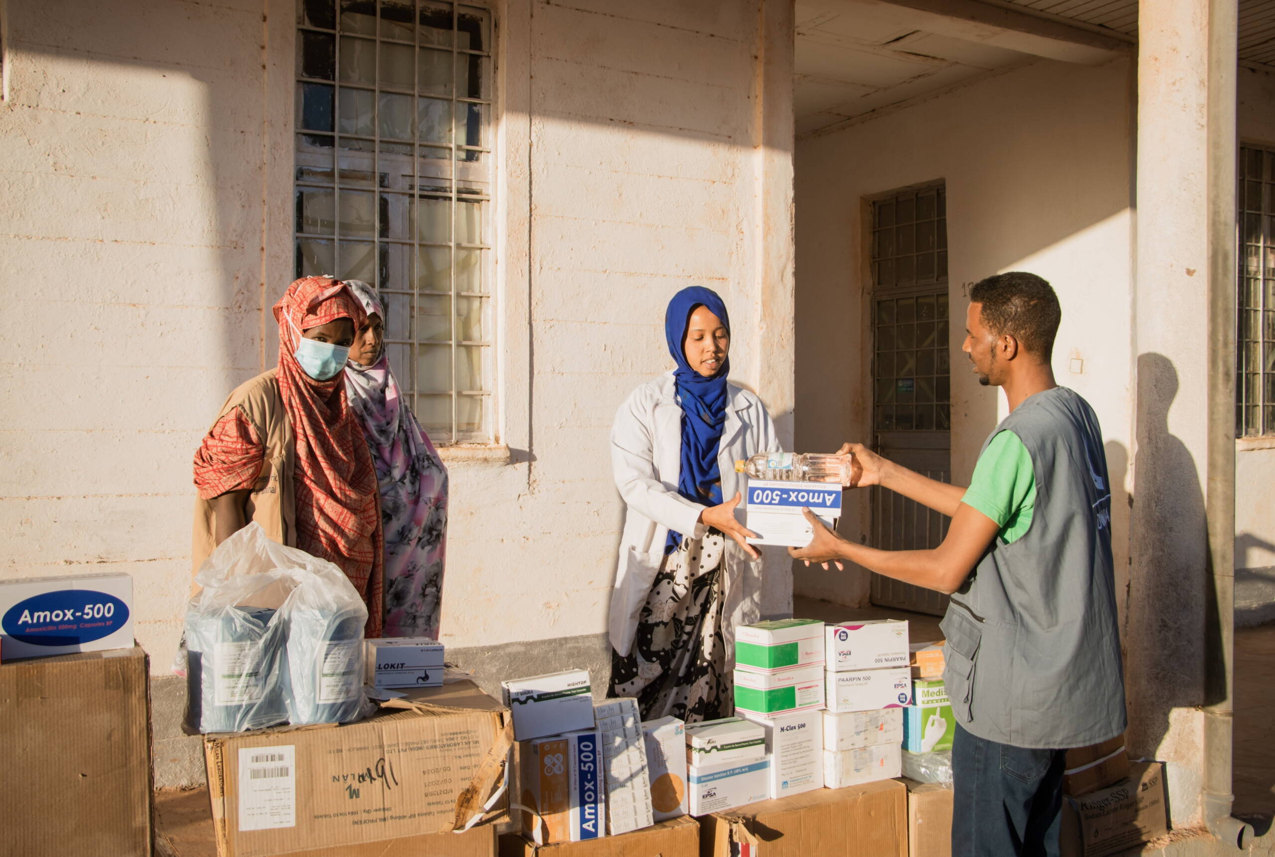 Ein Mann übergibt einer Gesundheitsmitarbeiterin Medikamenteschachteln.