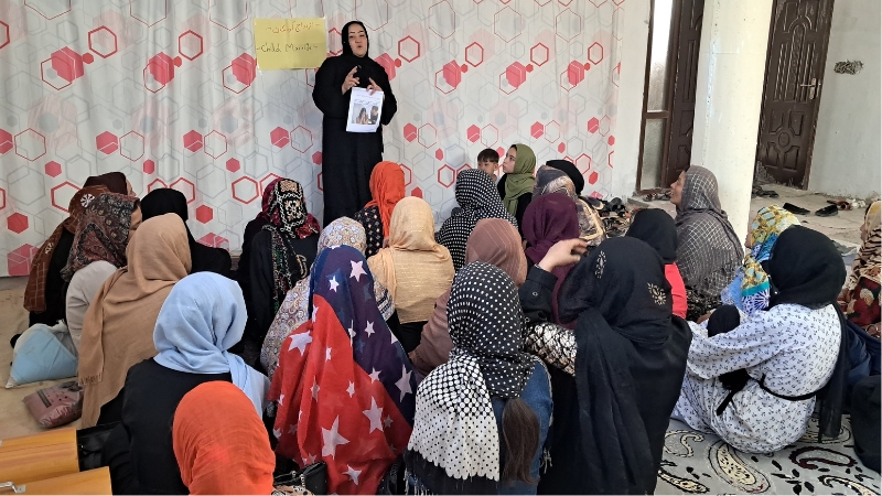 Eine Frau spricht vor einer sitzender Gruppe.