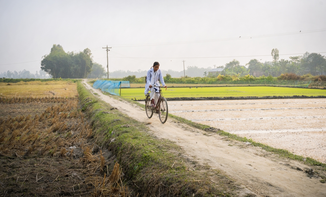 Ein Mädchen radelt auf einem Damm.