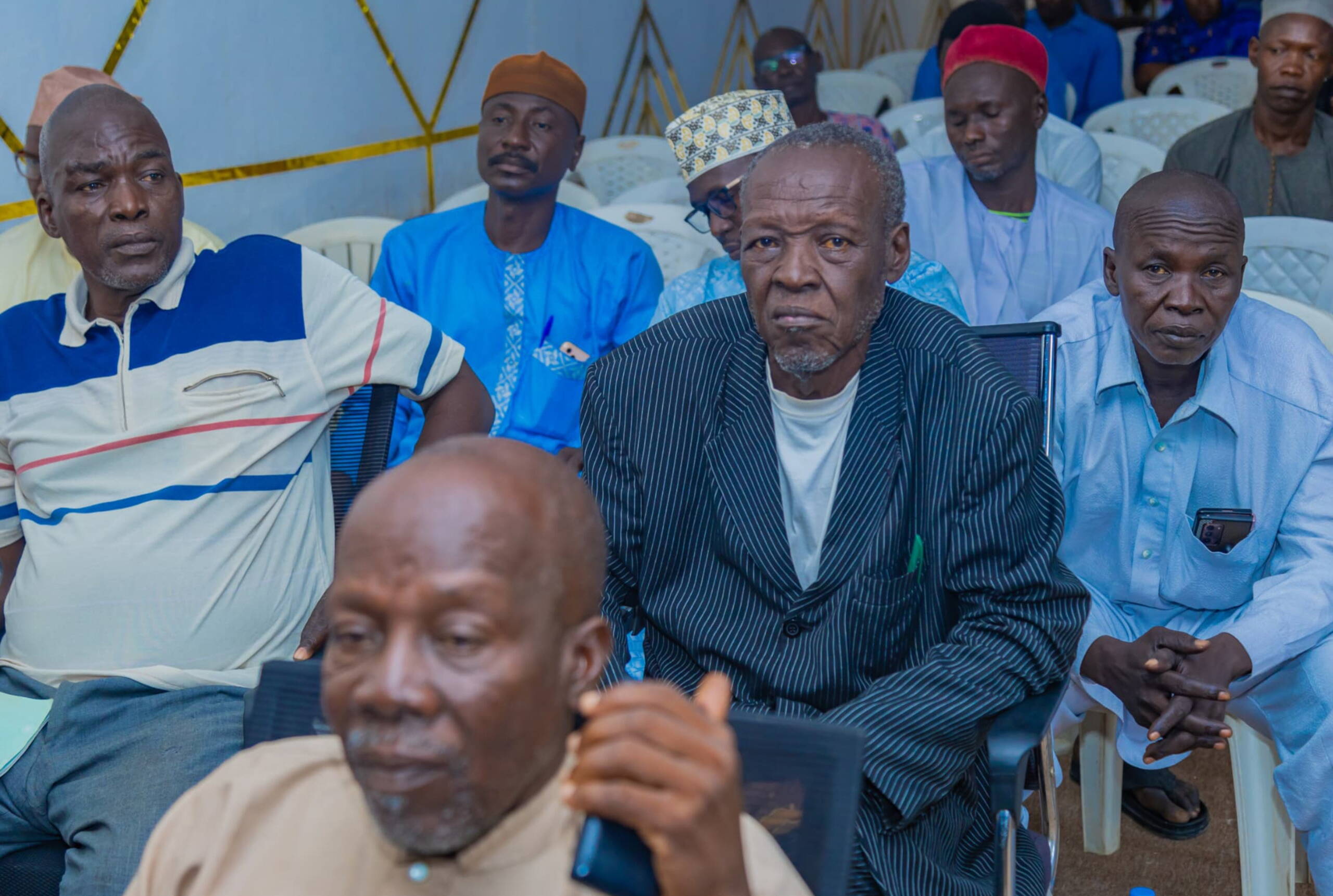 Sensibilisierung religiöse Führungspersonen Männer sitzen auf Plastikstühlen und hören zu.