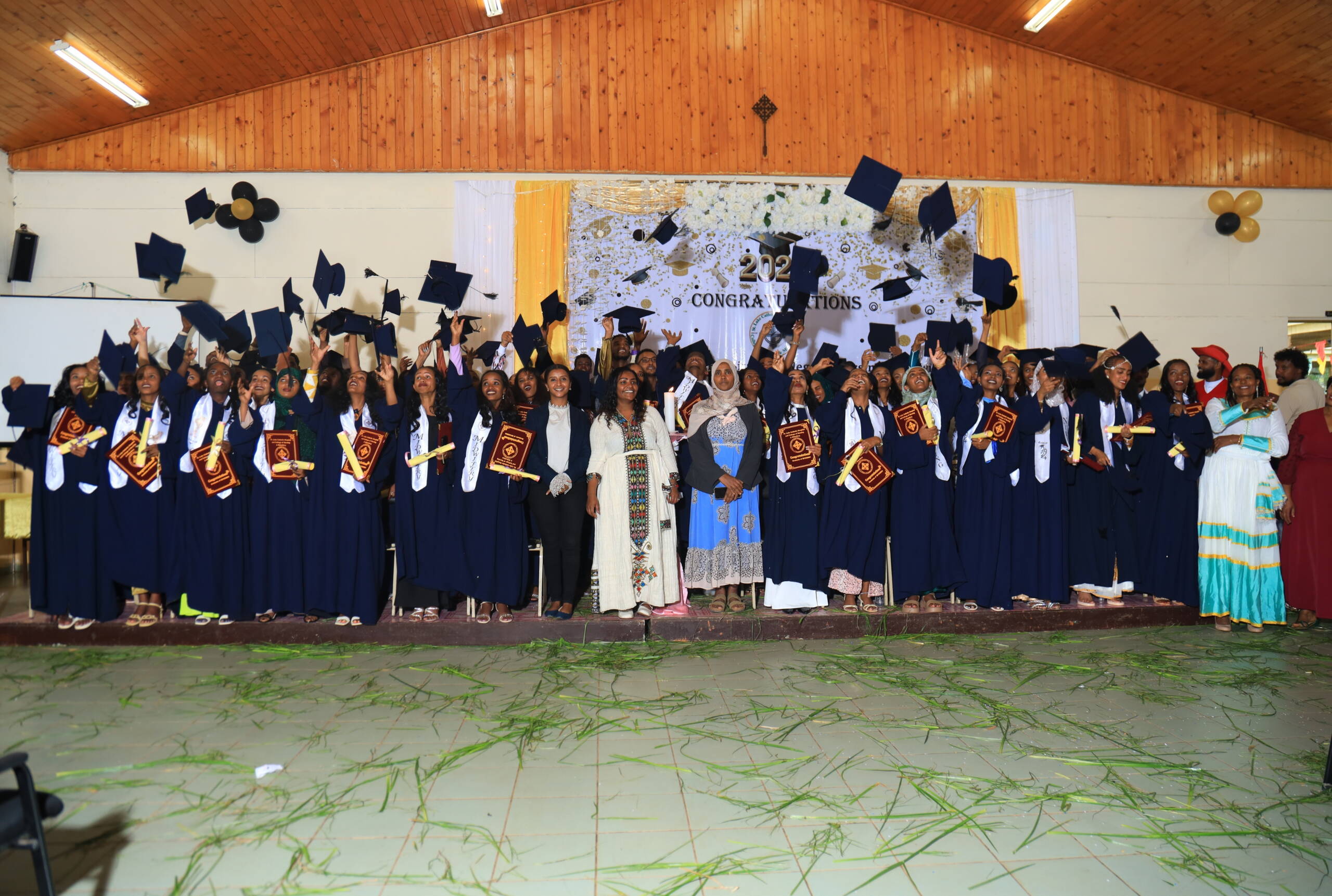 Eine Gruppe von Menschen steht aufgereiht, alle werfen ihre Hüte in die Höhe.