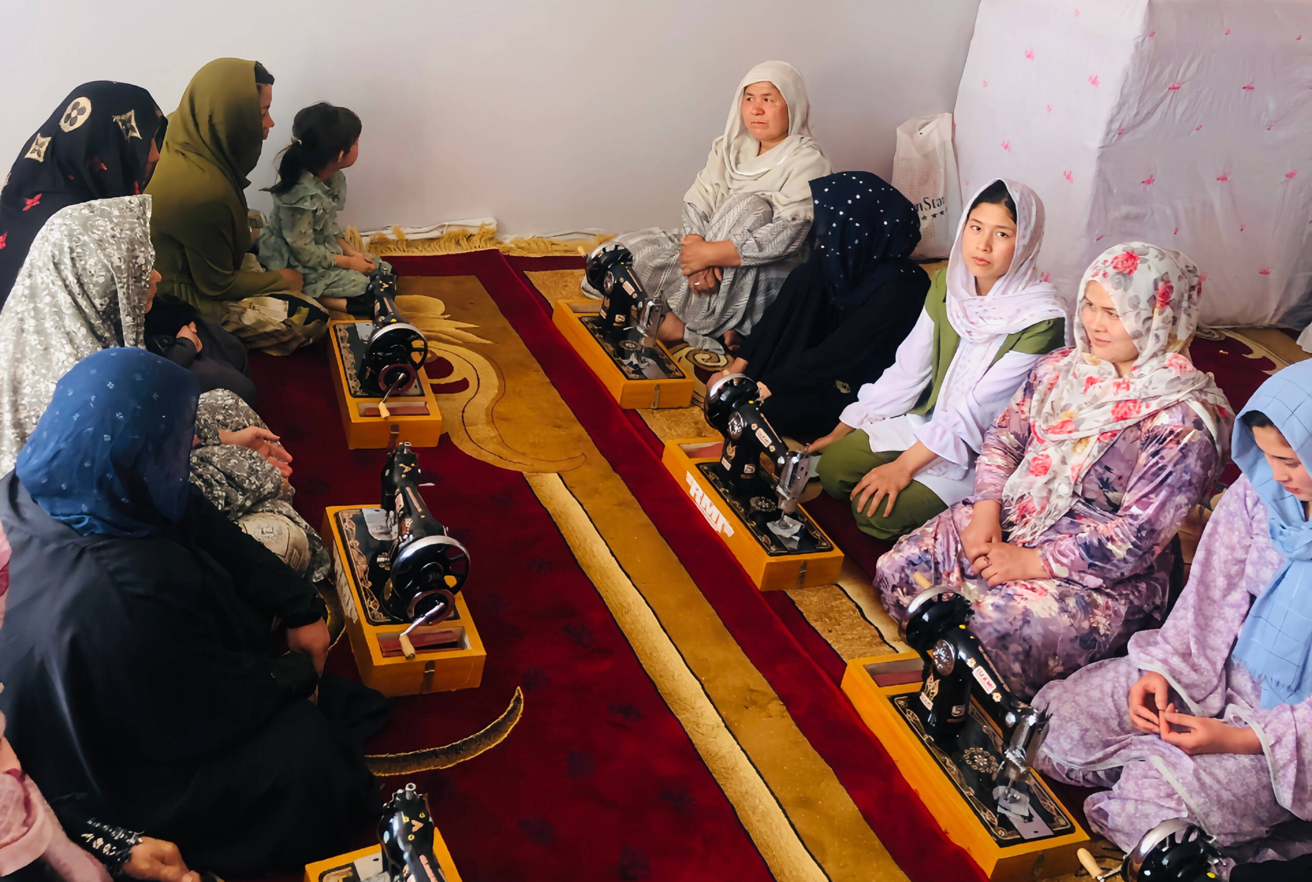 Frauen sitzen hinter Nähmaschinen.