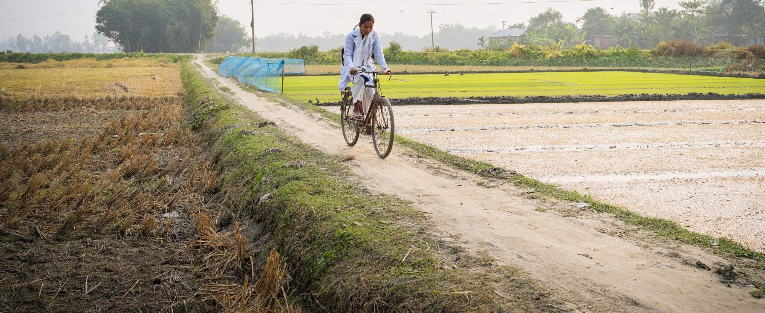 Schulweg Ein Mädchen radelt auf einem Damm zur Schule.