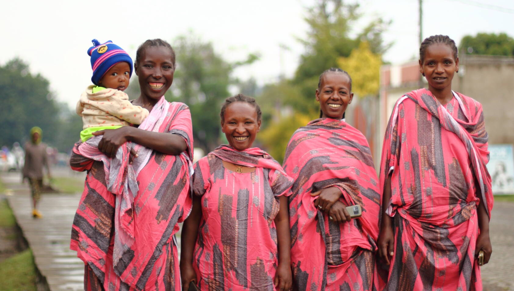 Vier Frauen stehen auf einer Strasse und lachen stolz in die Kamera.