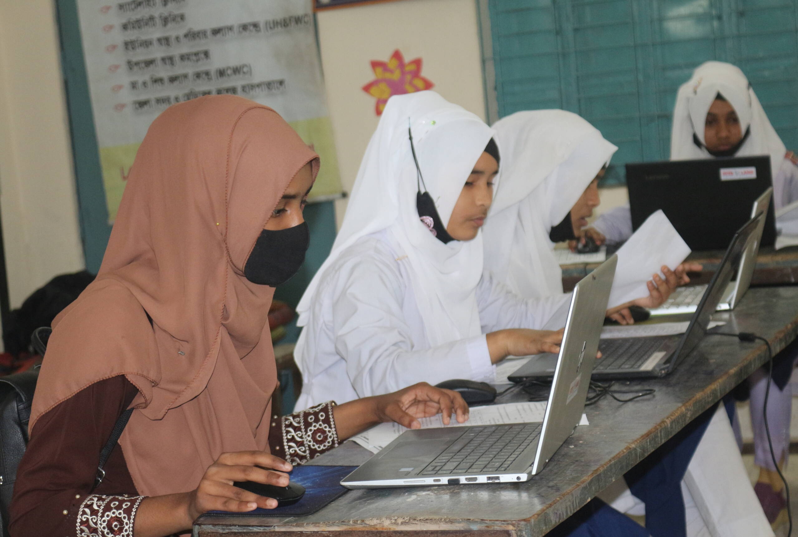 Mädchen sitzen hinter Computer und lernen.