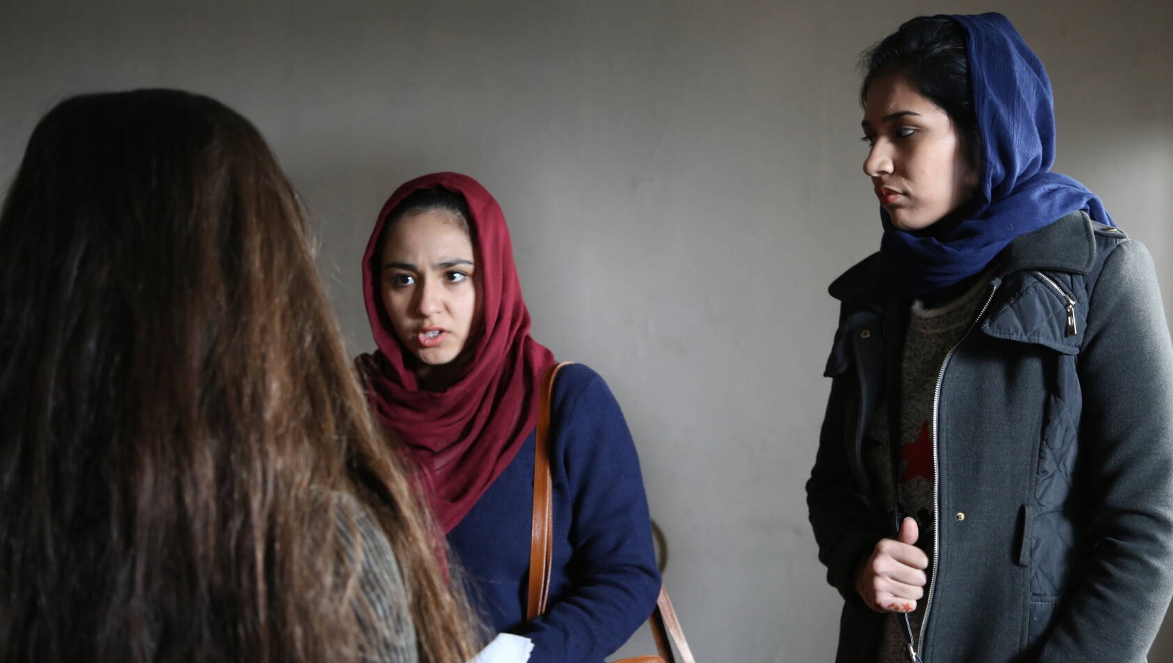 Szene aus dem Film Hava, Maryam, Ayesha Zwei junge Frauen sprechen zu einer dritten Frau, die mit dem Rücken zur Kamera steht.