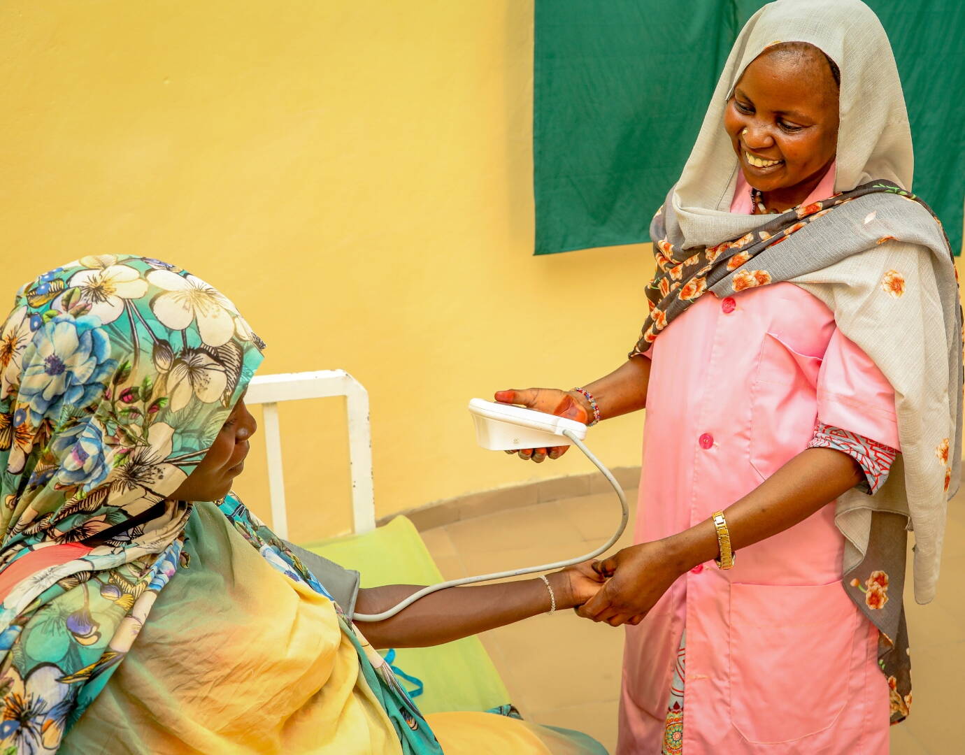 Eine Hebamme misst den Blutdruck einer schwangeren Frau.