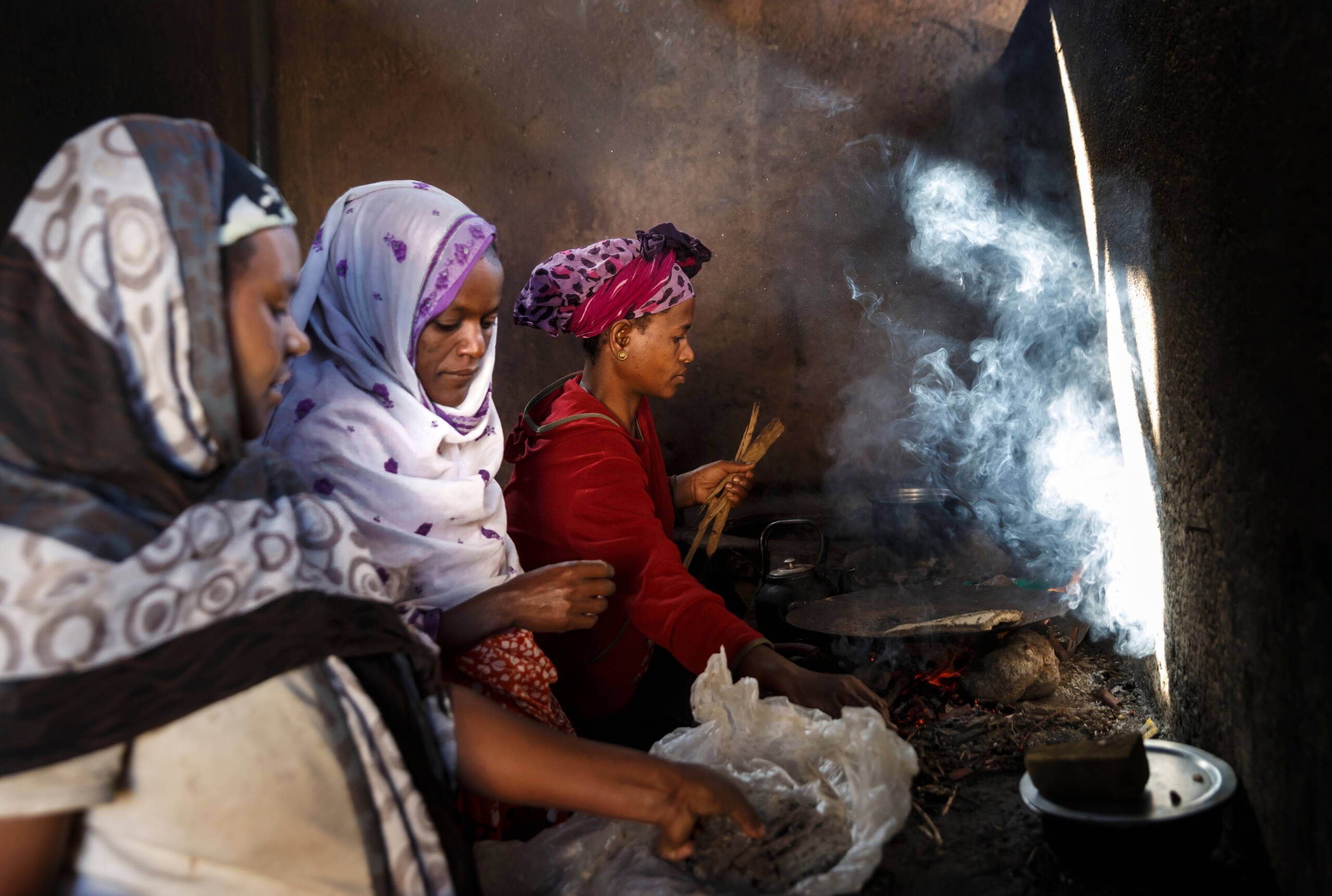 Schwangere Frauen stehen vor Feuer und kochen.
