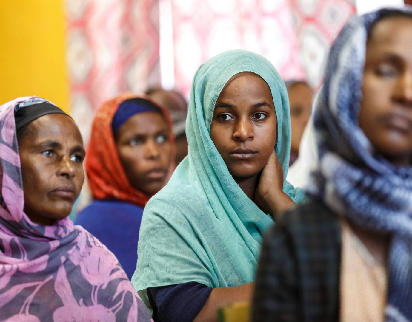 Mehrere Frauen hören einer Rede zu, eine Frau schaut in die Kamera.