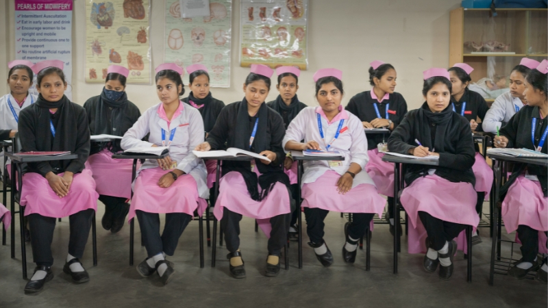 Hebammen: Leben retten als Beruf Eine Gruppe junger Frauen sitzt in der Schule, Bücher vor sich.