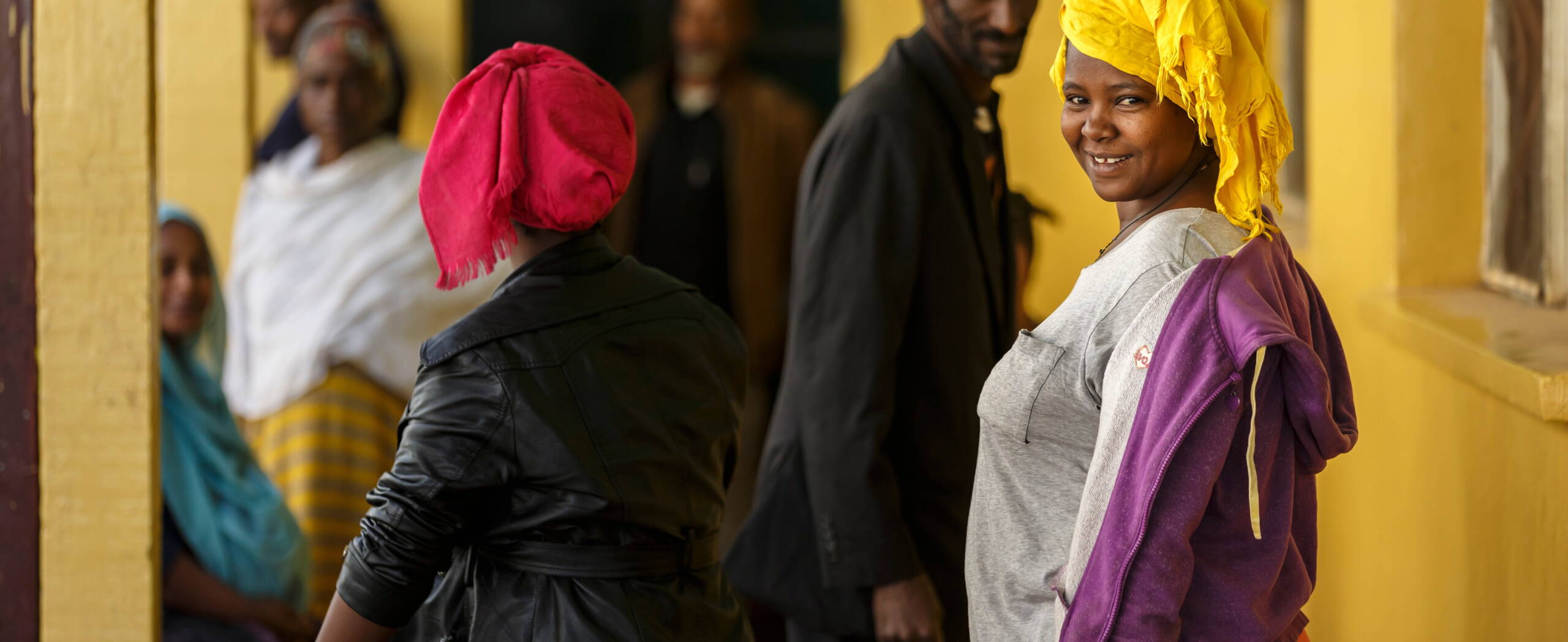 Frau Äthiopien Attat Eine Frau steht in einer Warteschlange und lächelt in die Kamera.