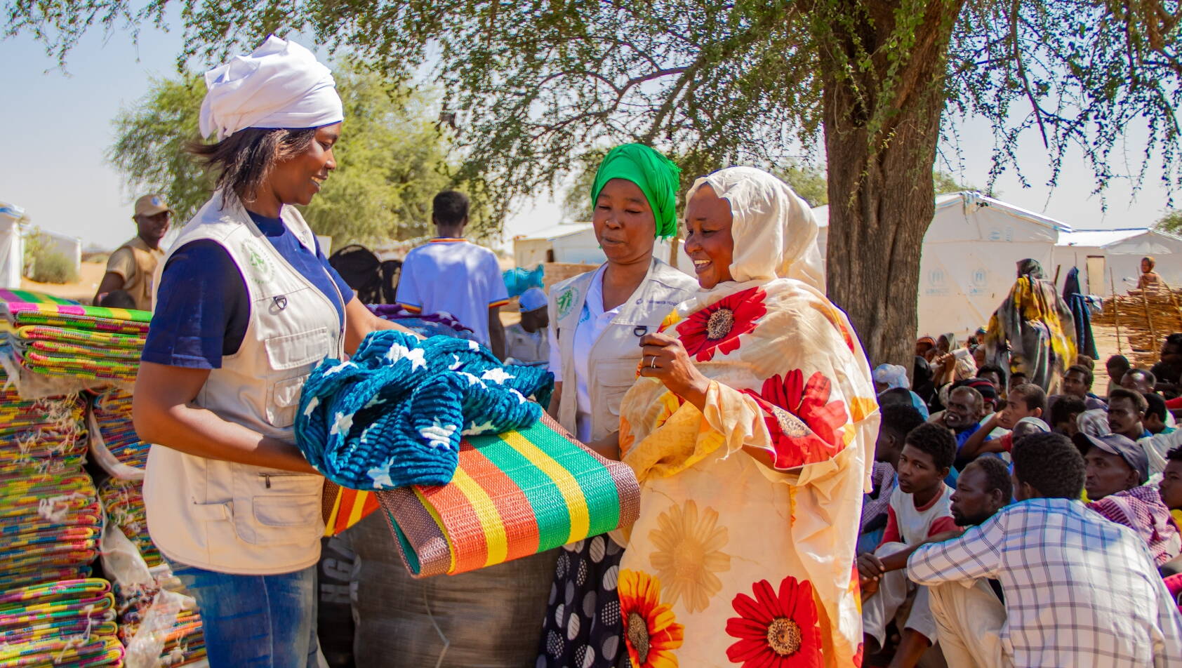 Zwei Mitarbeiterinnen von BASE verteilen Decken und Matten.