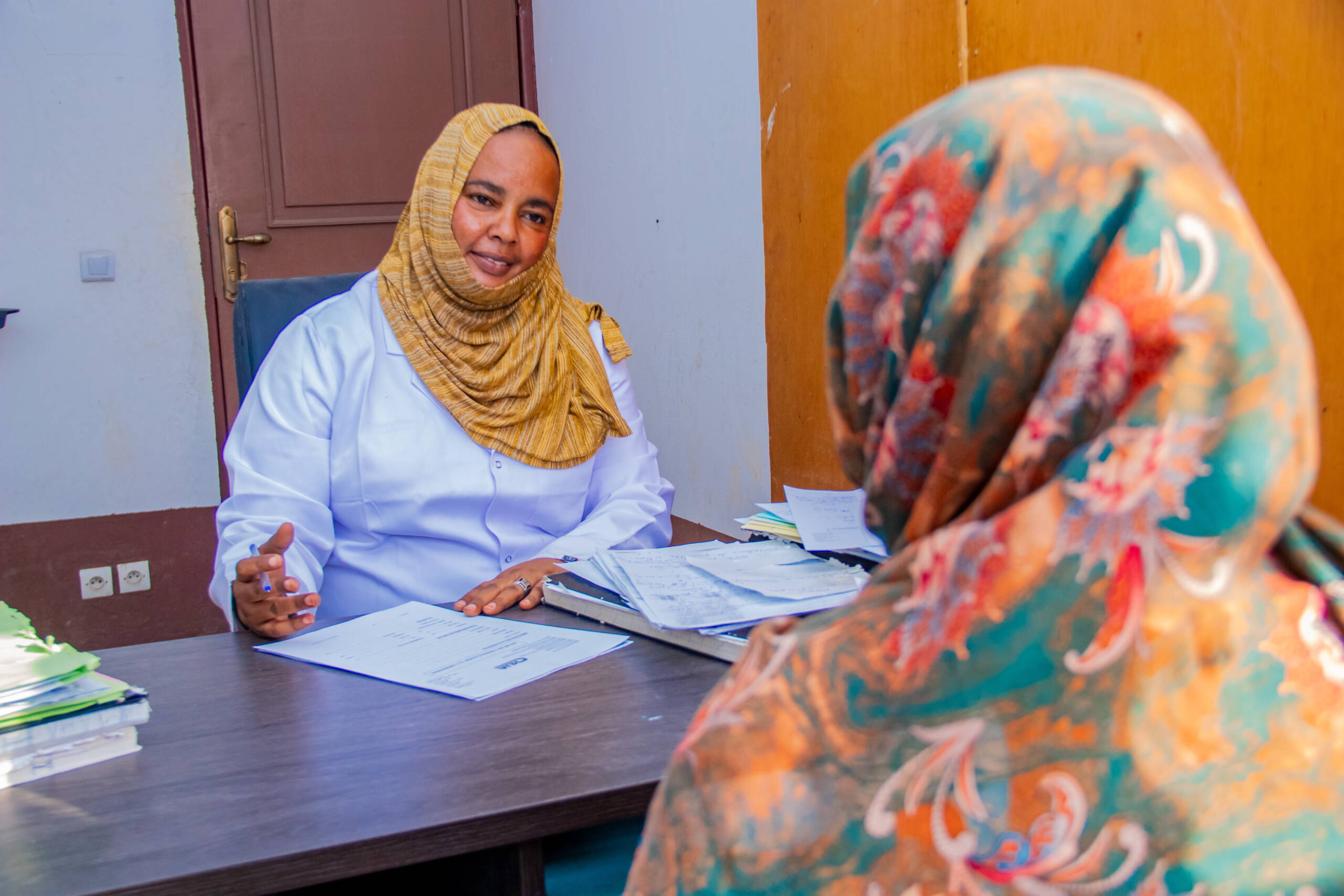 Eine Frau sitzt am Tisch und berät eine andere Frau.