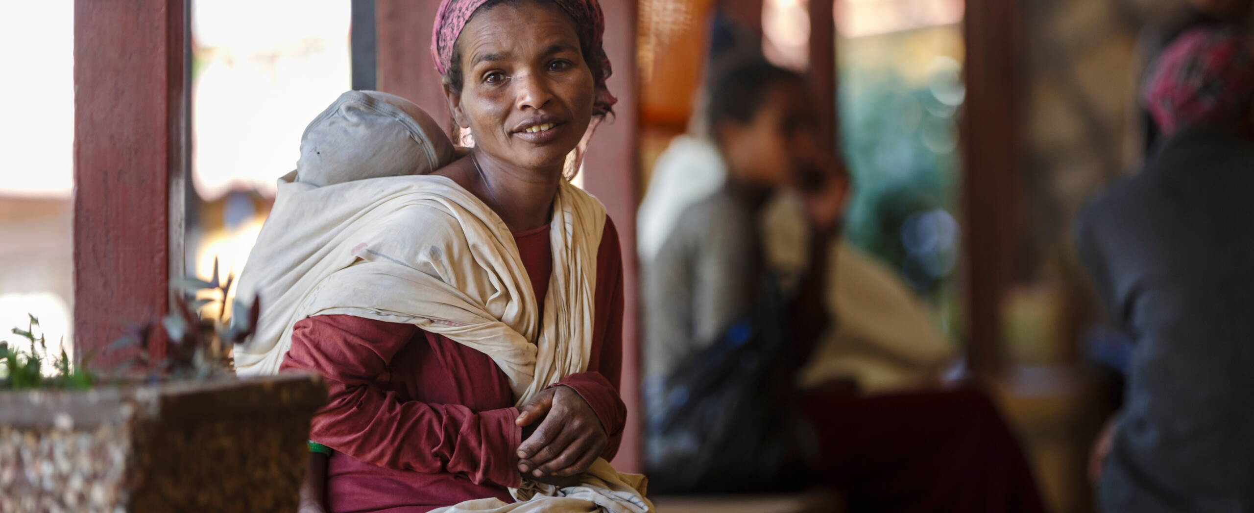 Mutter und Baby Eine Mutter mit Baby auf dem Rücken schaut in die Kamera.
