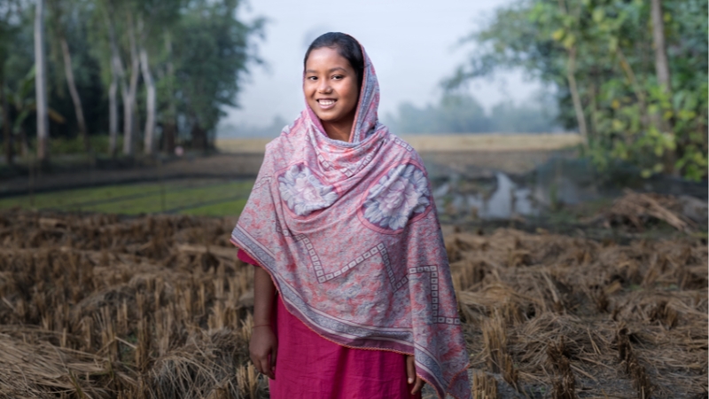 Eine junge Frau lacht stolz in die Kamera.