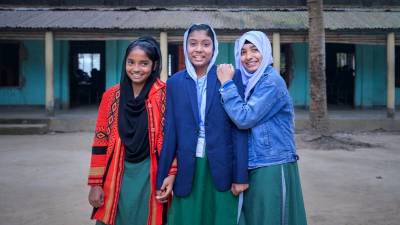 Kinderehen bekämpfen – gemeinsam und umfassend Drei Mädchen lehnen sich lachend aneinander.