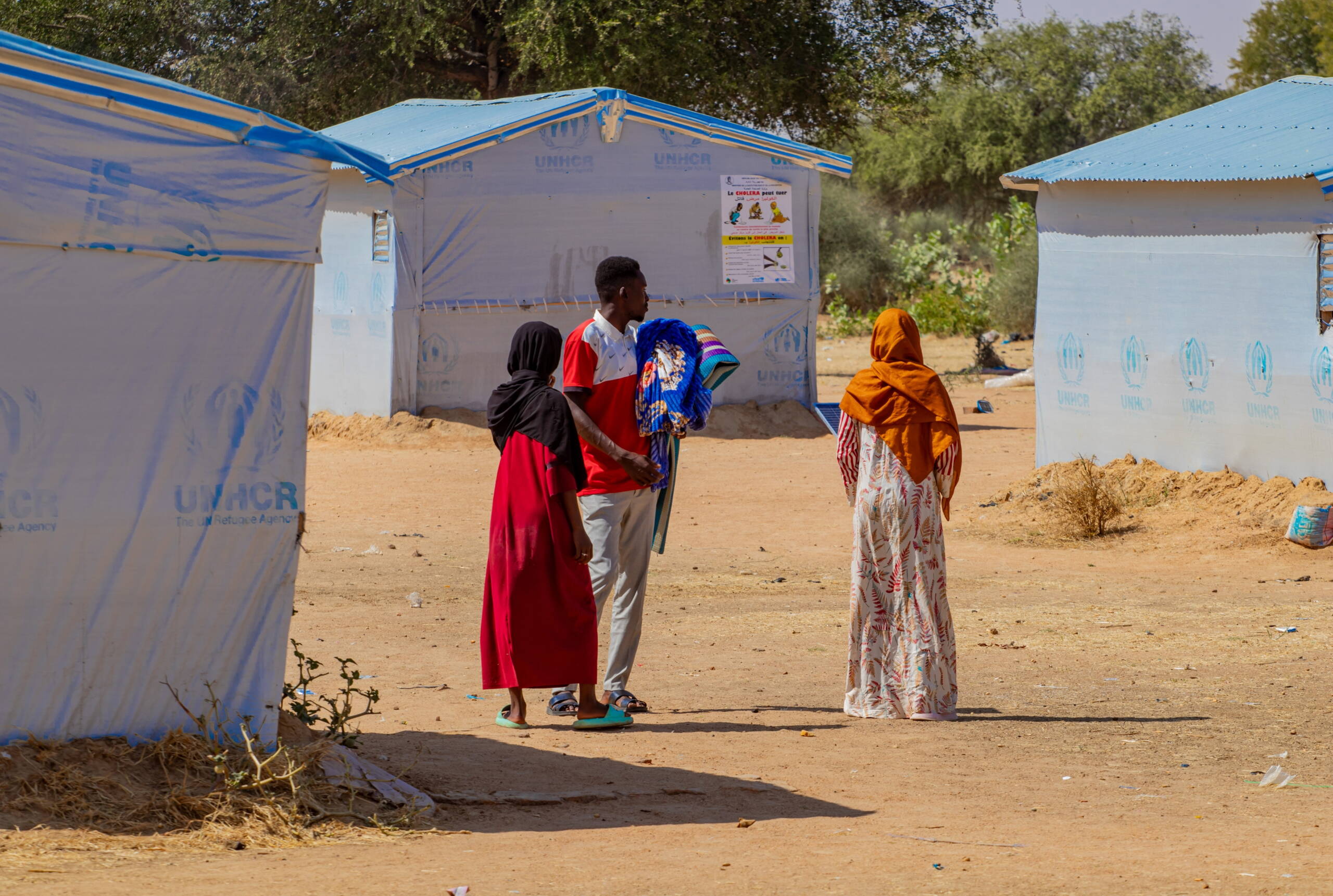 Menschen stehen vor Zelten des UNHCR.