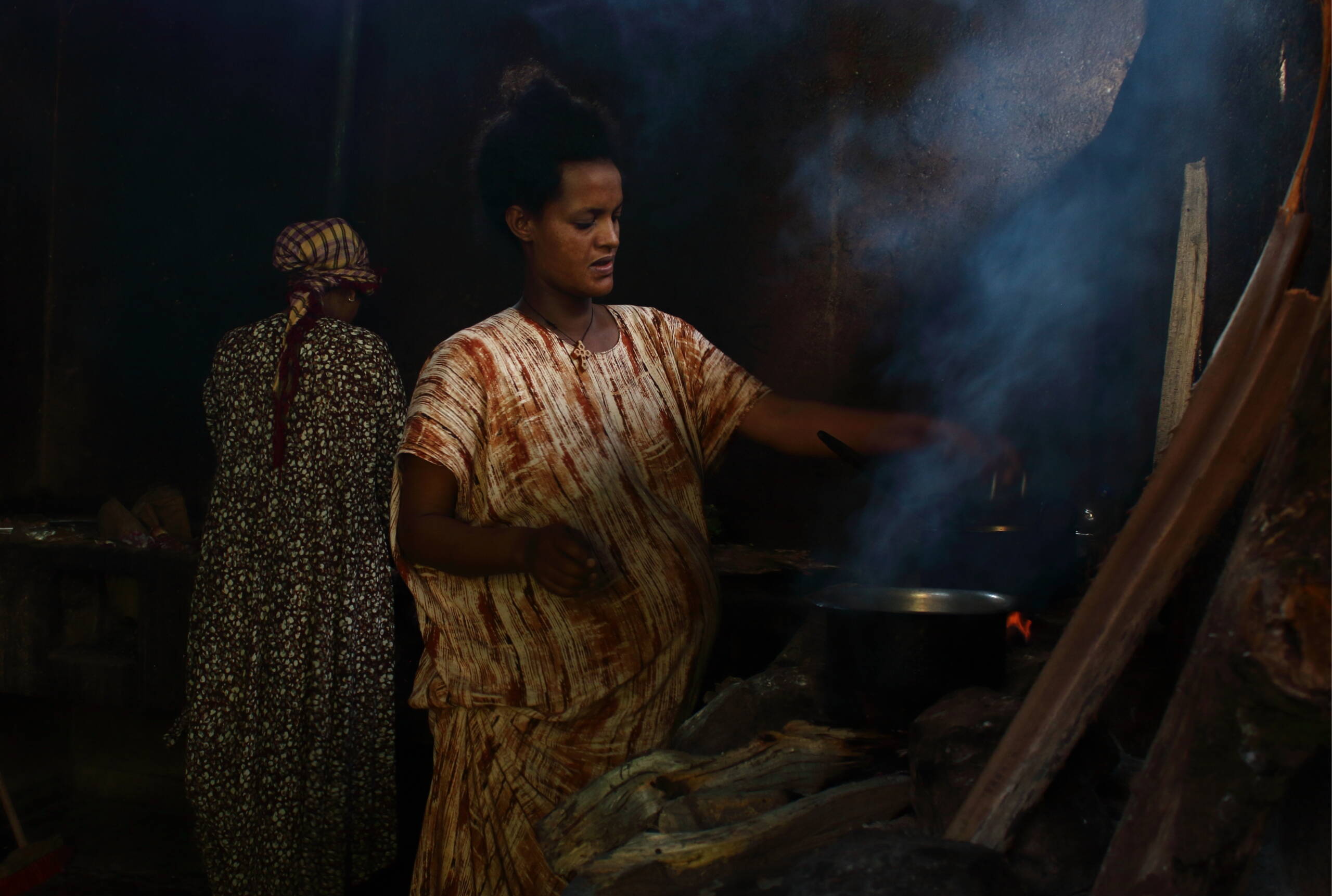 Schwangere Frauen stehen vor Feuer und kochen.