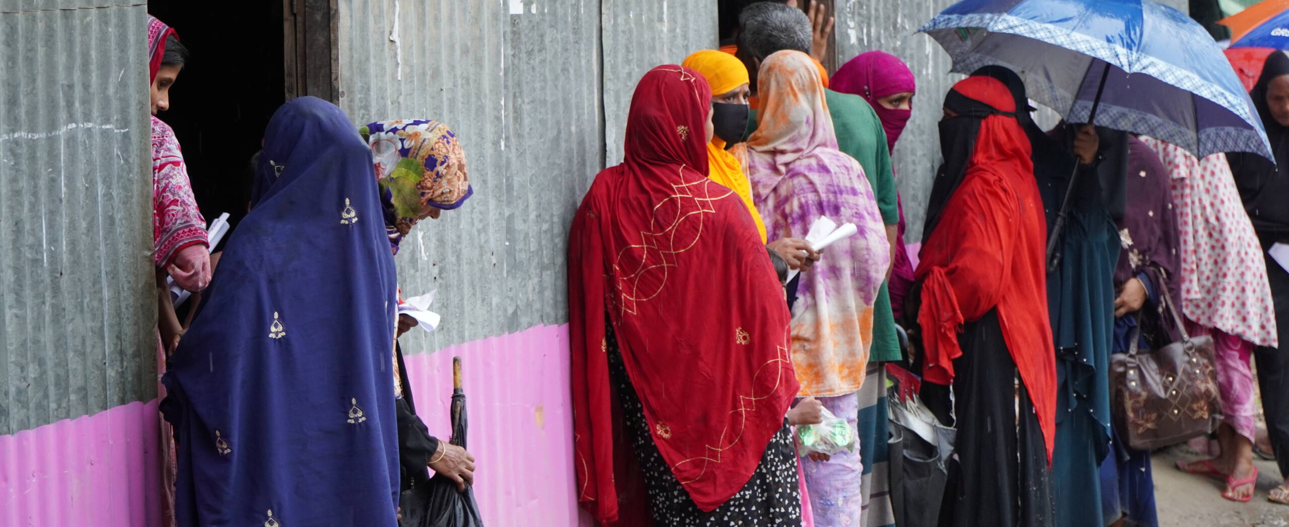 Nothilfe aufgrund von Fluten, Bangladesch Frauen stehen im Regen an um Medikamente zu erhalten.