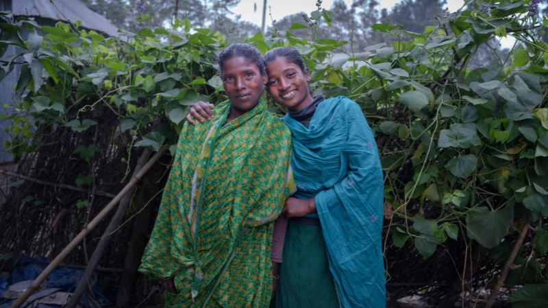 Mutter und Tochter Bangladesch Mutter und Tochter lehnen aneinander und lächeln in die Kamera.