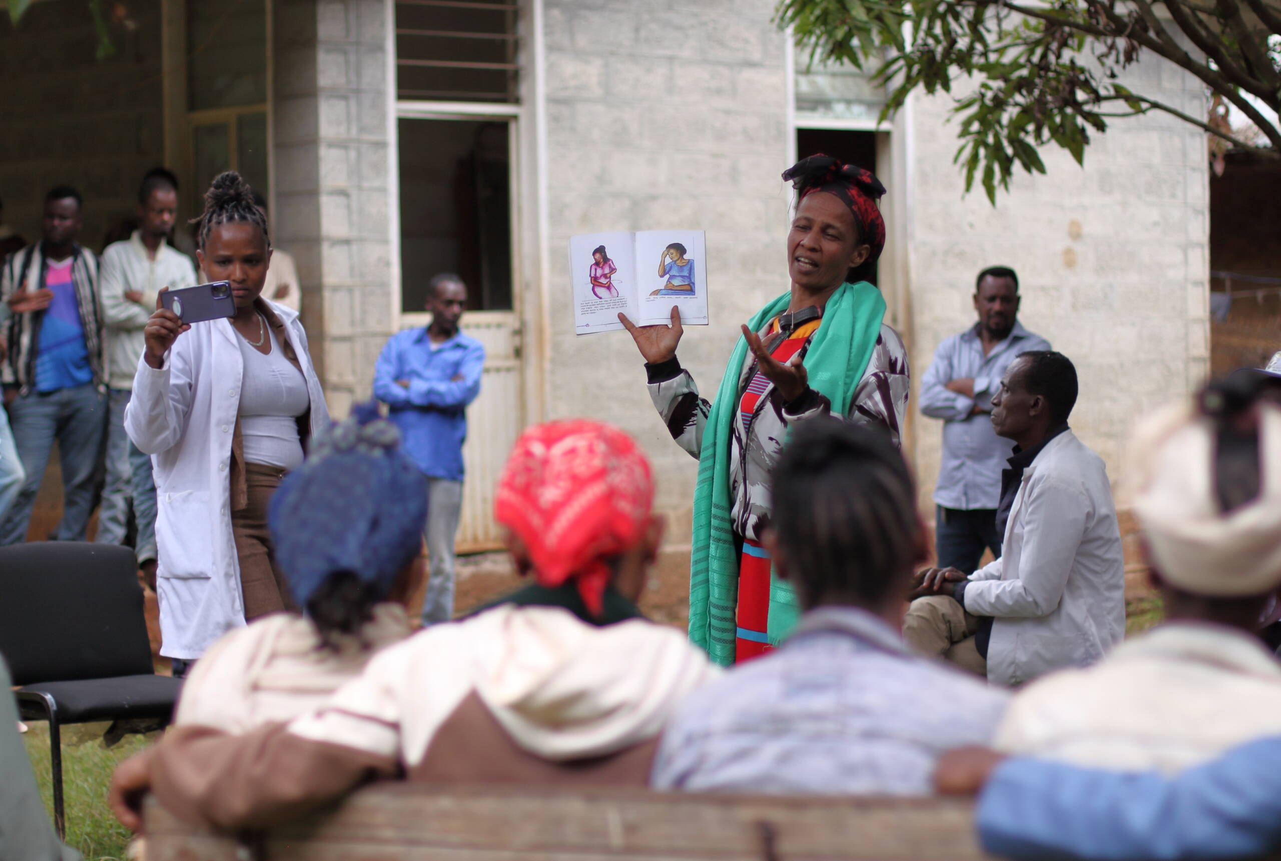 Eine Frau steht vor anderen Frauen und hält eine Illustration mit schwangeren Frauen hoch.