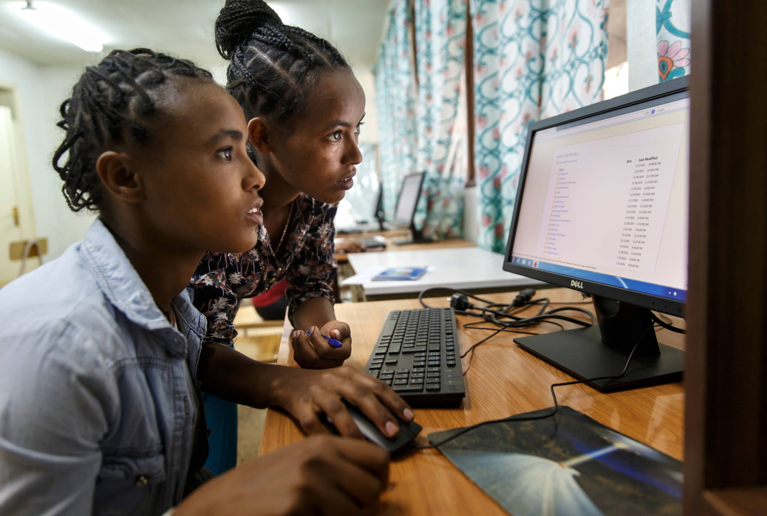 Zwei Studentinnen sitzen vor einem Computer und schauen konzentriert in den Bildschirm.