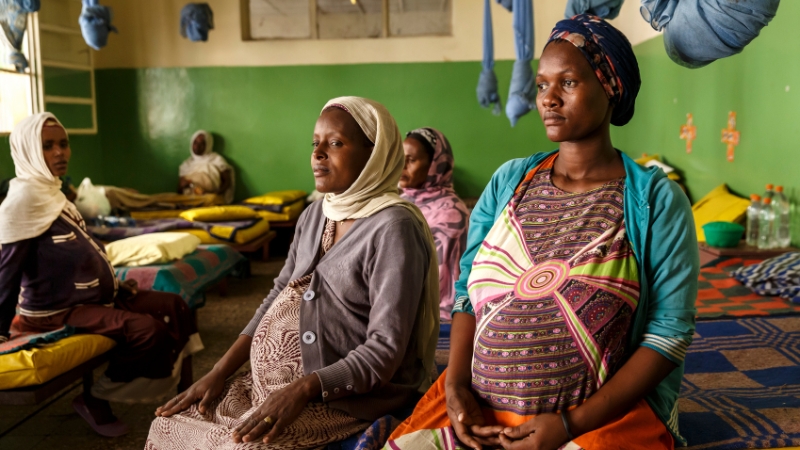 Schwangere Frauen sitzen auf Bett und warten.