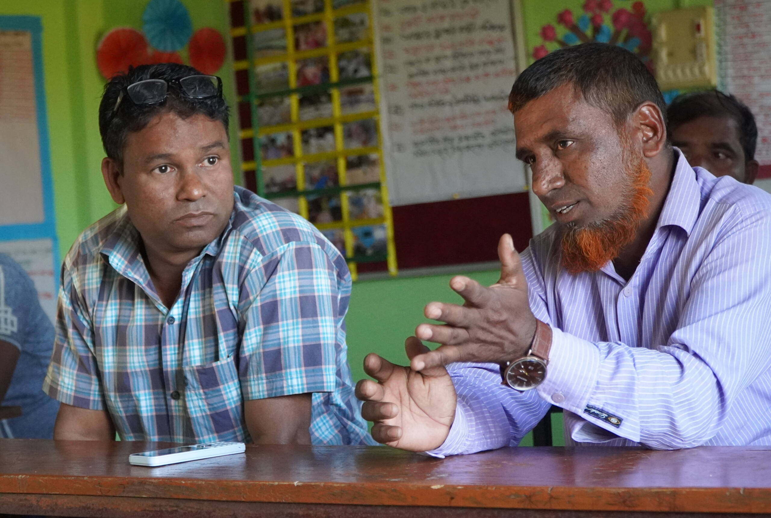 Zwei Männer sitzen nebeneinander und reden.
