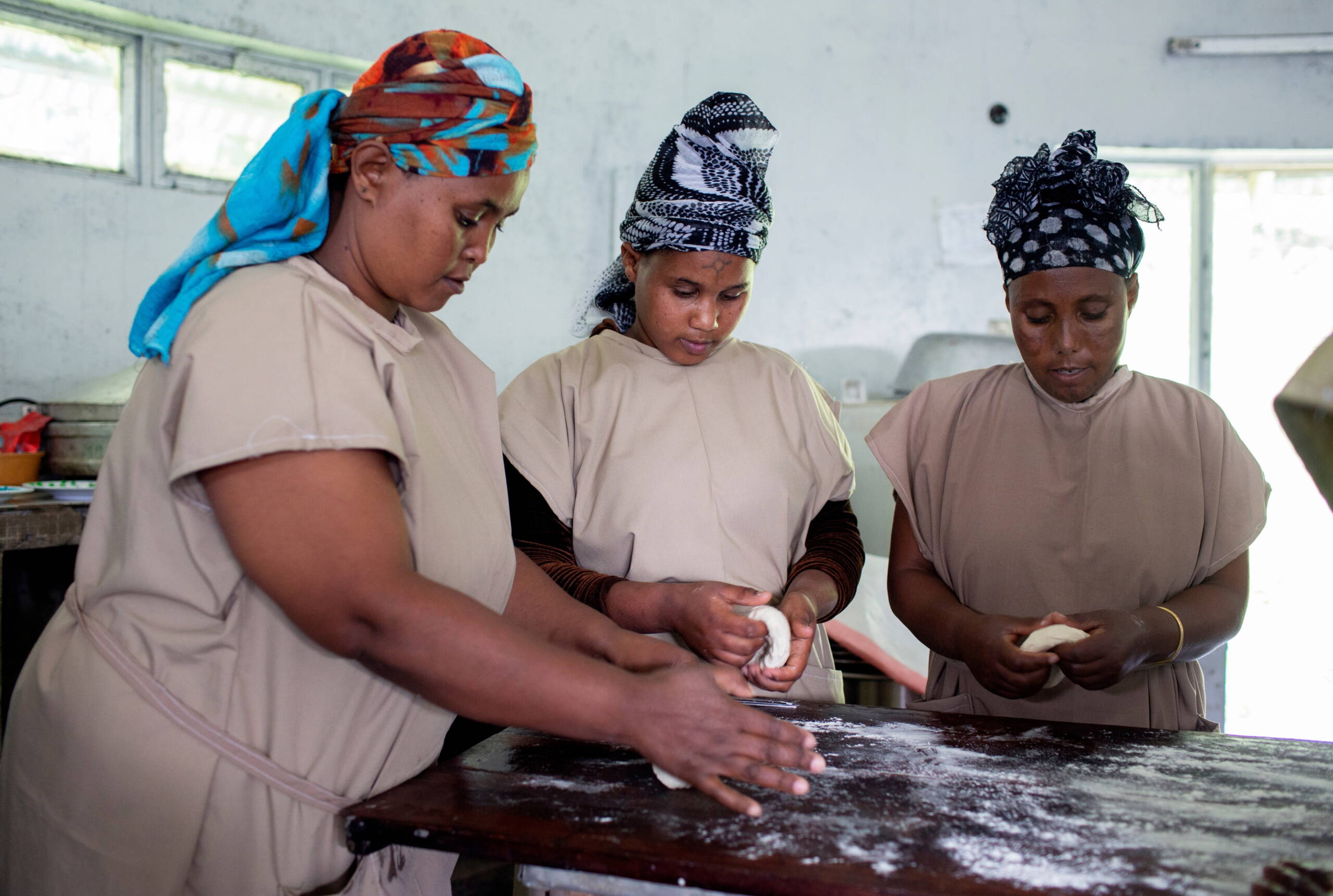 Drei Frauen kneten Teig.