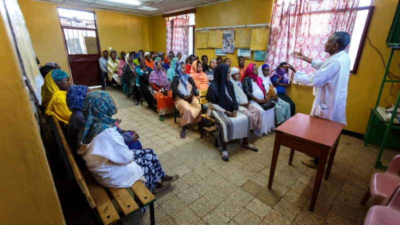Attat In einem Schulungsraum sitzen viele Menschen, ein Mann erklärt etwas.