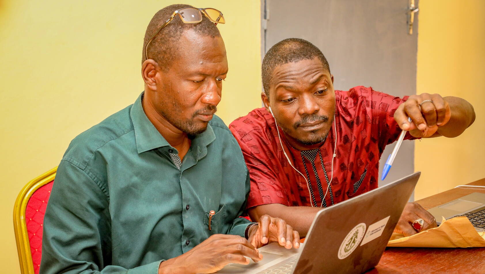 Zwei lokale Mitarbeitenden im Tschad vor dem Laptop. 