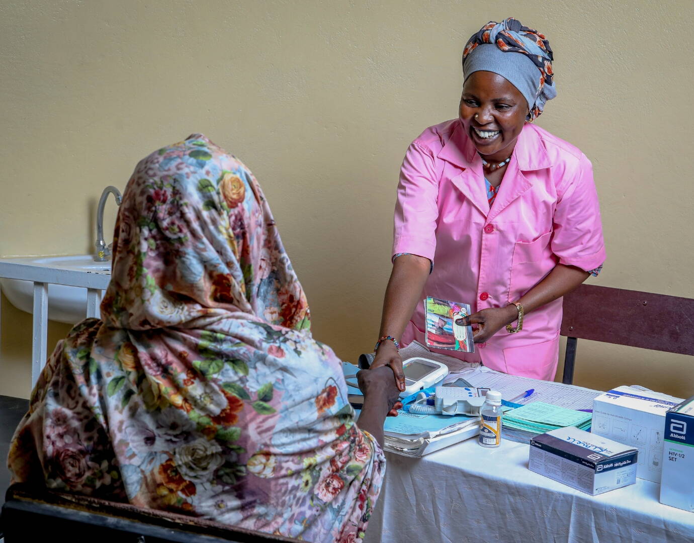 Jetzt spenden! Eine Hebamme empfängt eine schwangere Frau und schüttelt lächelnd ihre Hand.