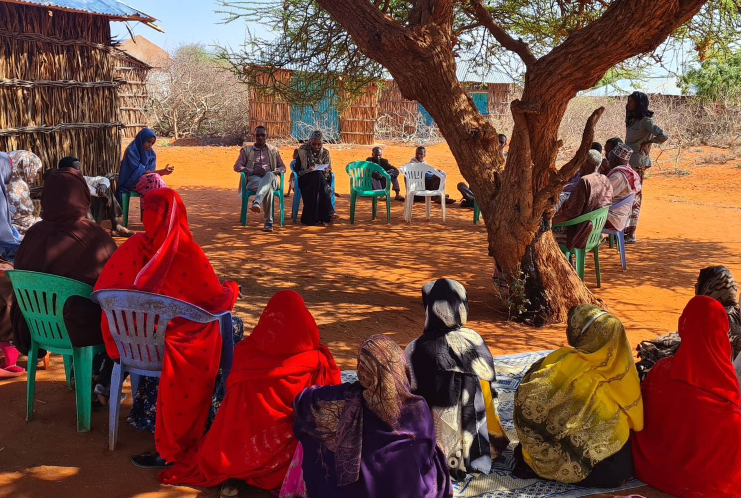 Gemeinschaftsbefragung Menschen sitzen in einem Kreis auf Stühlen und am Boden.