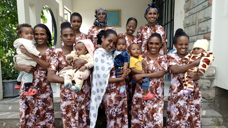 Eine Gruppe Mütter steht auf einer Treppe, die meisten halten ein Kleinkind auf den Armen.