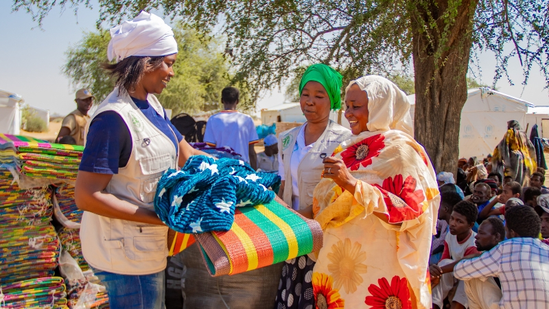 Eine Frau verteilt Decken an eine andere Frau.