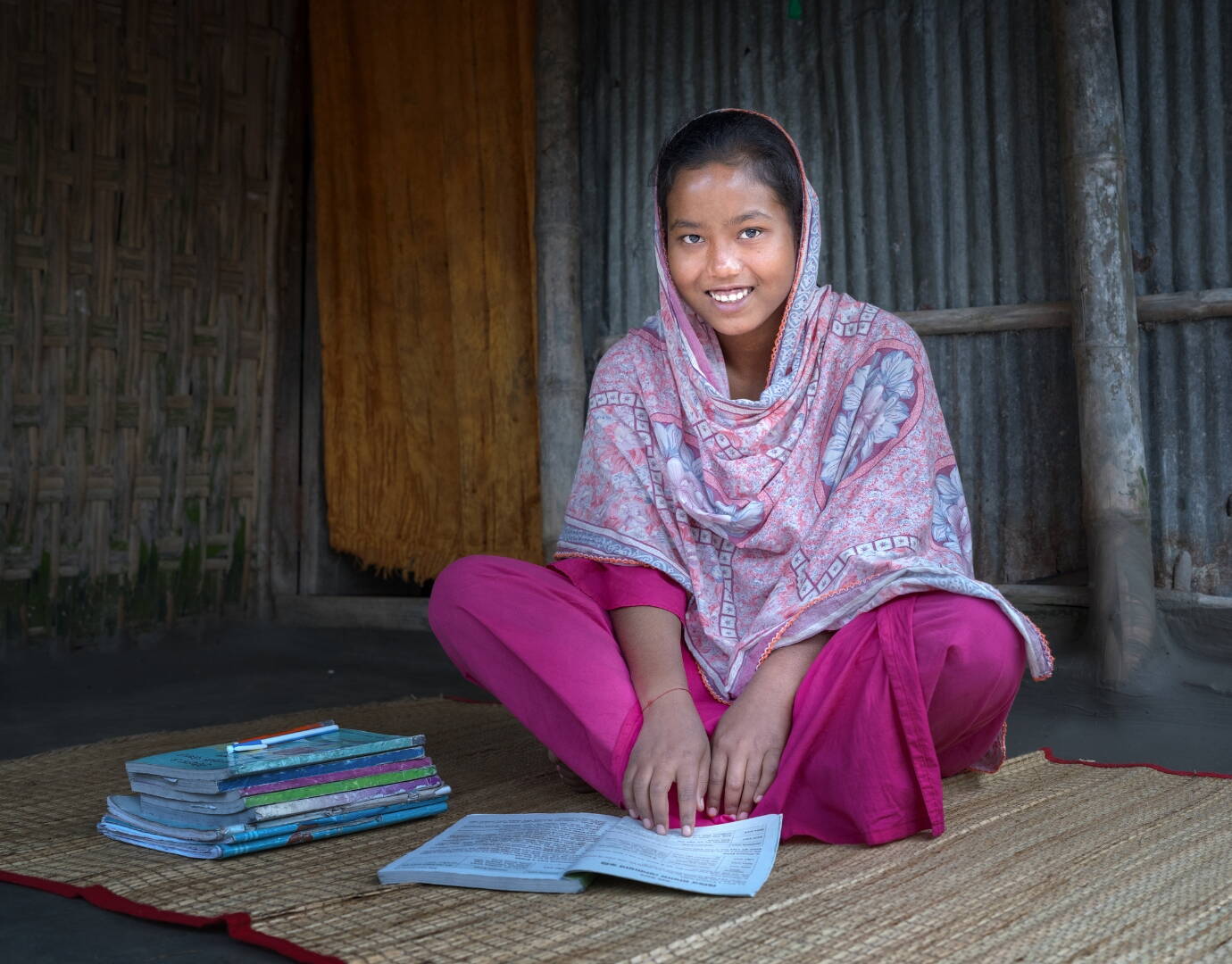 Ein Mädchen sitzt am Boden, vor ihm liegt ein Heft.
