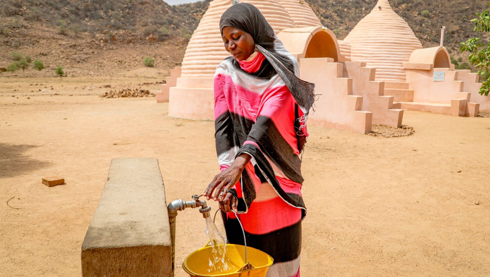 Frau schöpft Wasser von einer Wasserstelle im Tschad