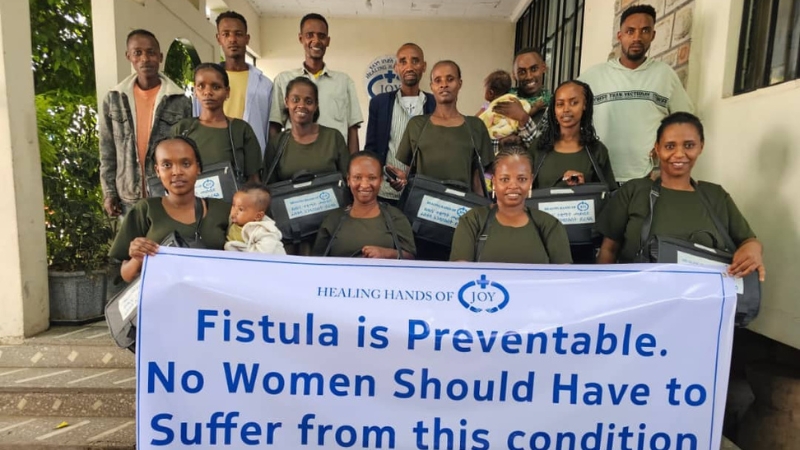 HHoJ Frauen halten ein Plakat zum Thema Geburtsfisteln in die Höhe.