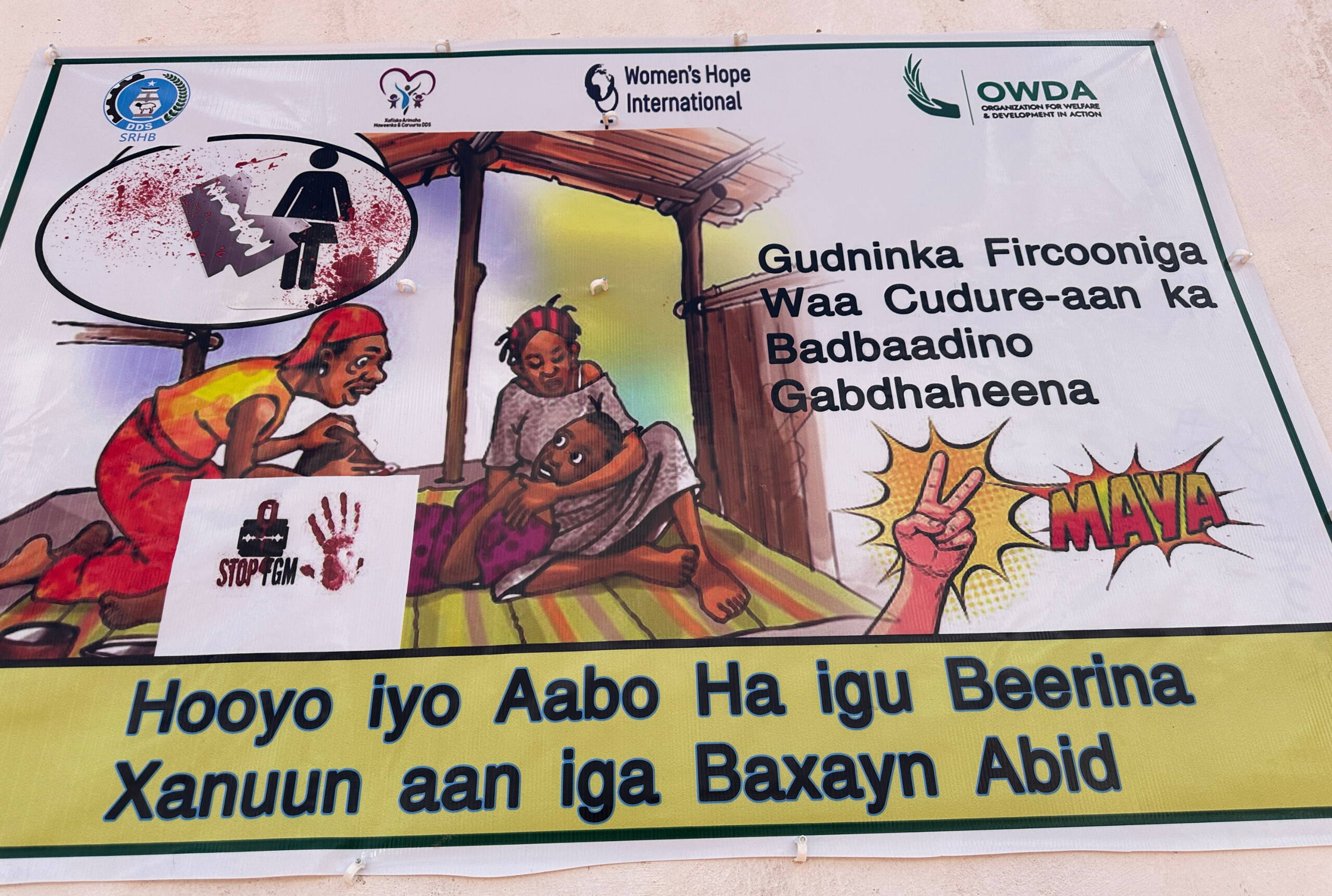 Sensibilisierung FGC Grafik auf Papier aufgedruckt: Eine Frau beschneidet ein Kind, darunter ein Stop-Zeichen.