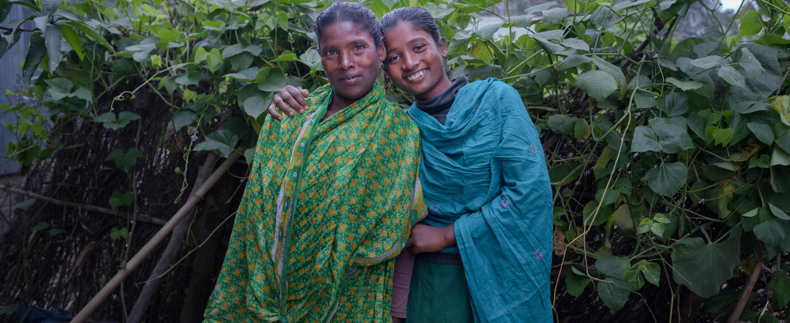 Mutter und Tochter in Bangladesch Muter und Tochter stehen aneinander gelehnt und lächeln in die Kamera.