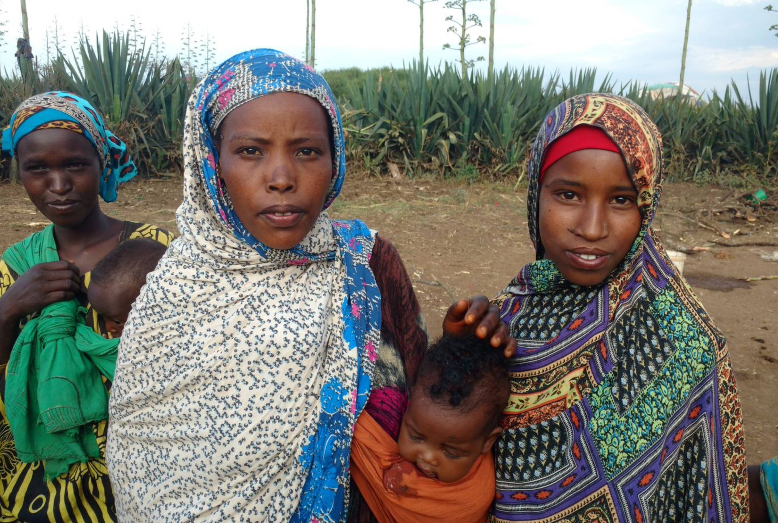 Drei Frauen, zwei davon tragen Babys in einem Tragetuch.