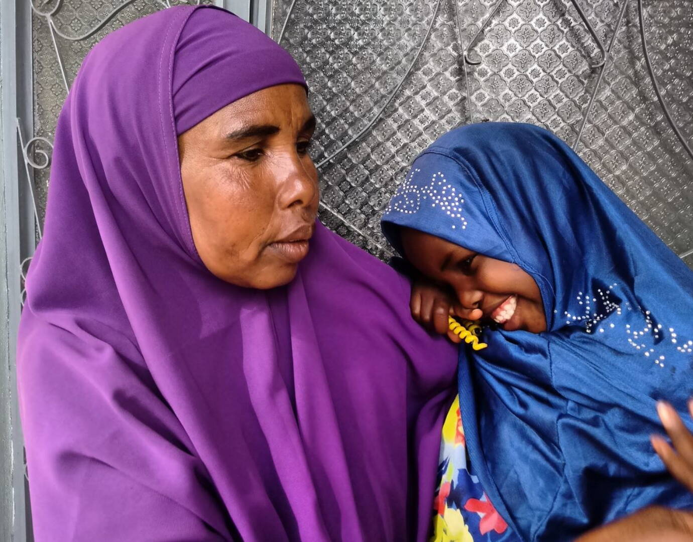 Ein Mädchen kuschelt sich vertrauensvoll an eine ältere Frau.