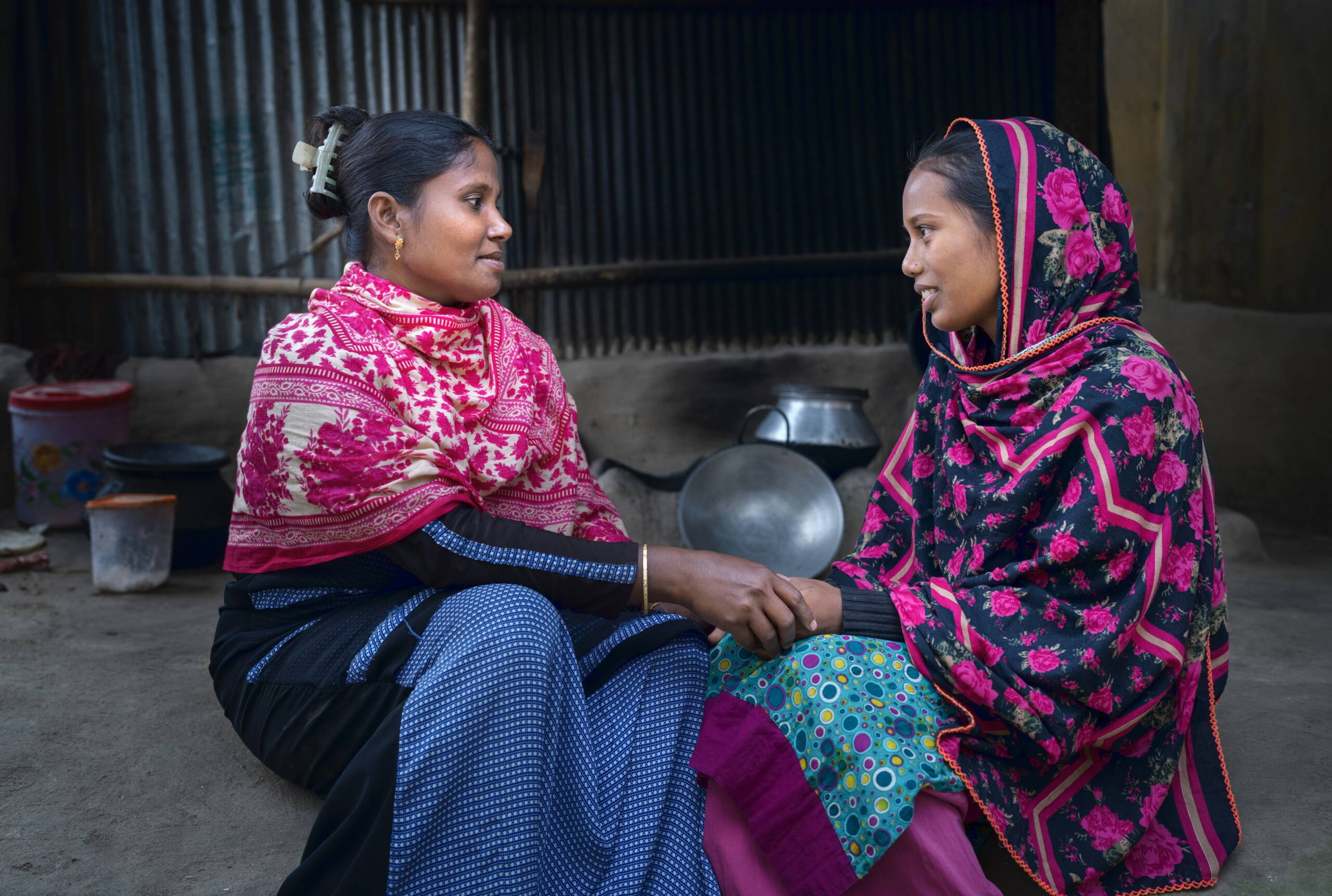 Eine Frau hält die Hände einer Teenagering, sie schauen sich vertrauensvoll an.
