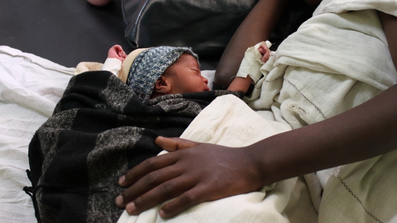 Schützende Hand von Mutter über Neugeborenem in einem unserer Partnerspitäler