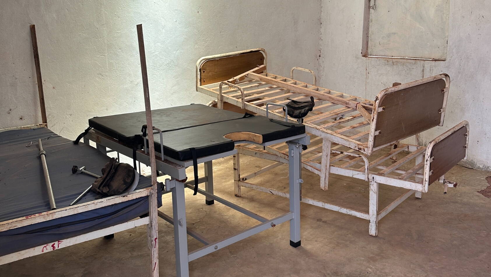 Rostige Betten und ein Behandlungstisch stehen in einem Raum mit dreckigen Wänden.