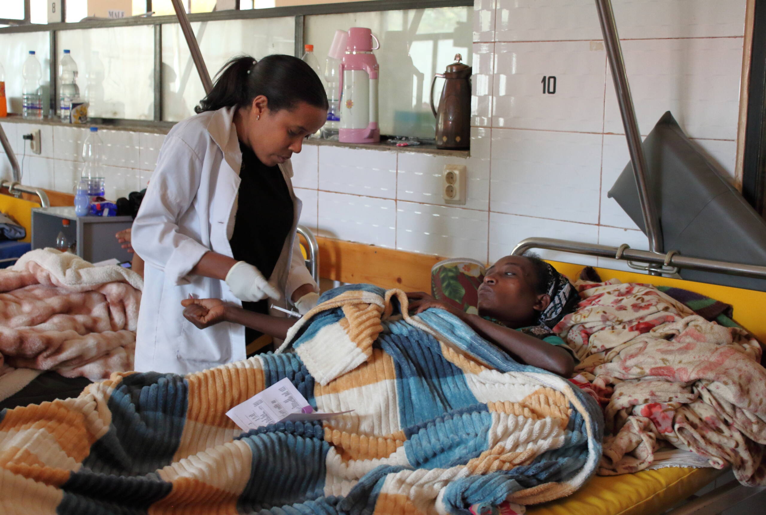 Eine Krankenschwester steht am Bett einer Patientin.